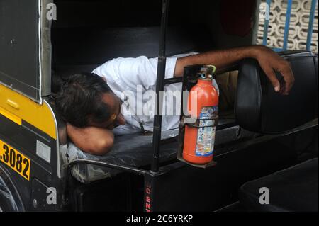 Mumbai, Maharashtra, Inde- Asie, 11 juillet 2020 - pilote indien Auto Rickshaw prenant le repos dans le siège arrière de Rickshaw Banque D'Images