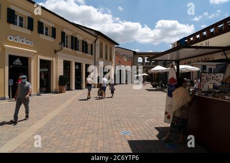 SERRAVALLE SCRIVIA, ITALIE - JUILLET 12 2020 - beaucoup de gens achetant des articles de mode au début de la boutique de créateurs Vente saison de port masque après covid Banque D'Images