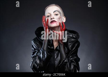 Image d'une femme en imperméable noir aux mains rouges Banque D'Images