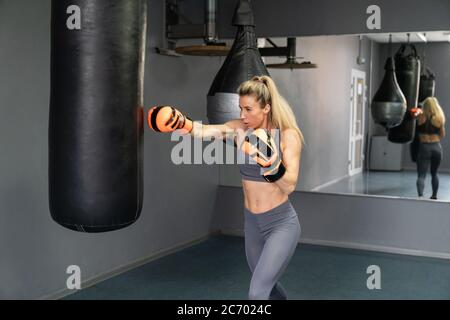 Jeune femme portant des gants de poinçonnage en train de faire de la boxe à la salle de gym Banque D'Images