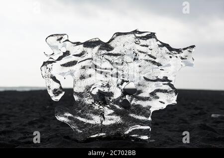 Floe de glace transparent sur la plage de sable noir, Islande, lagon de Jokulsarlon Banque D'Images