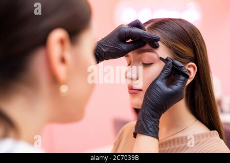 un maquilleur applique du henné sur les sourcils dans un salon de beauté. Banque D'Images