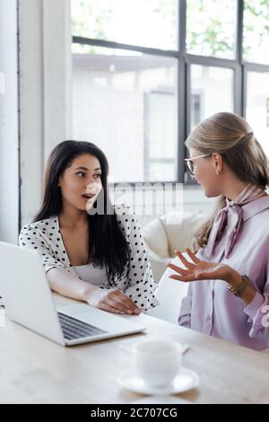 une attention sélective aux femmes d'affaires qui se racolent près d'un ordinateur portable dans un bureau moderne Banque D'Images