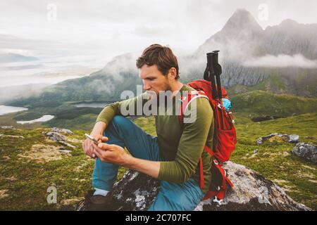 Homme randonneur utilisant la navigation d'application de smartphone dans les montagnes blogueur de voyage influent style de vie randonnée aventure été voyage extérieur backpacking dedans Banque D'Images