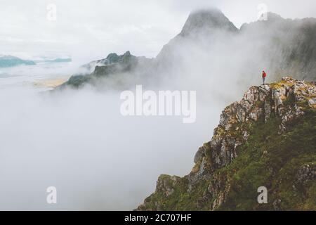 Homme voyageur dans les montagnes brumeuses sur le bord de falaise rocheuse solo Voyage actif style de vie aventure en plein air vacances en Norvège Banque D'Images