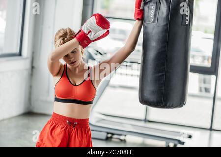 épuisé sportswoman en gants de boxe debout près du sac de poinçonnage Banque D'Images