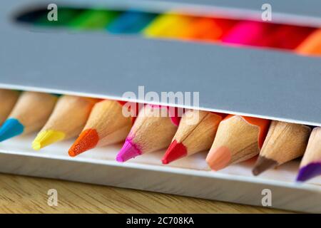 Crayons de couleur dans une boîte grise, couleurs arc-en-ciel, crayon orange colle macro, fournitures scolaires ou de bureau Banque D'Images