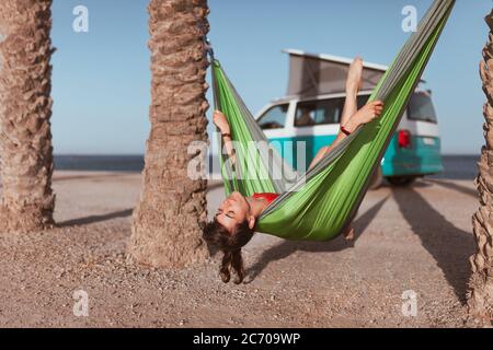 Femme couché dans un hamac entre des palmiers sur la plage Banque D'Images