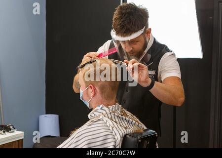 Carmarthen, Carmarthenshire, pays de Galles, Royaume-Uni. 13 juillet 2020. Un jeune homme a une coupe de cheveux dans Blue Street Barbers que les barbers et les coiffeurs rouvrent au pays de Galles avec l'assouplissement des restrictions de verrouillage de coronavirus / Covid-19. Crédit: Gruffydd Ll. Thomas/Alay Live News Banque D'Images