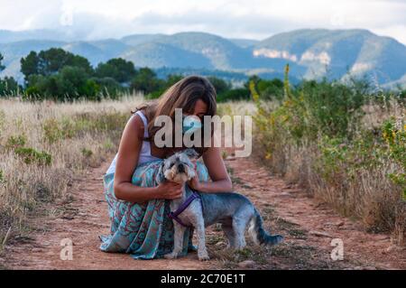 Jeune femme avec un masque de contrôle et prenant soin de son chien Banque D'Images