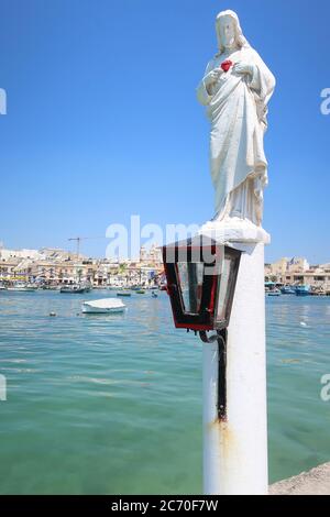 Statue représentant le Jésus située dans le port du village de pêcheurs de Marsaxlokk à Malte Banque D'Images