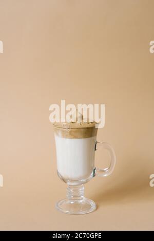 Magnifique Dalgon boire un café avec de la mousse dans un mug transparent sur fond beige Banque D'Images