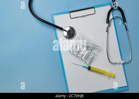 Stéthoscope, flacons de vaccin, seringue et document sur fond bleu. Vaccin contre la grippe coronavirus. Banque D'Images