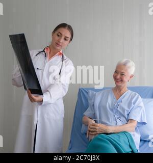 Patiente et médecin senior. Un jeune médecin a expliqué les résultats de l'examen du film radiographique aux patients âgés dans la salle de réveil. Banque D'Images