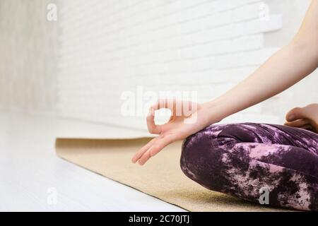 Femme pratiquant le yoga, se détendant dans Lotus poser sur le tapis. Padmasana exercice gros plan, mudra main et les pieds gros plan. Fille portant des vêtements de sport violets, méditant en studio de yoga ou à la maison. Banque D'Images