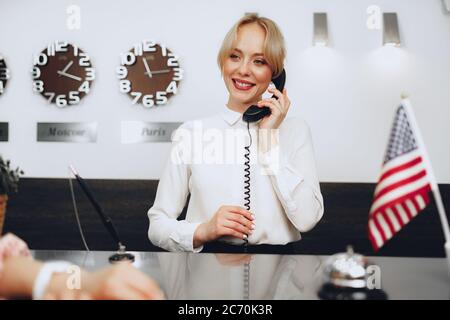 Une réceptionniste de l'hôtel parle au téléphone au travail Banque D'Images