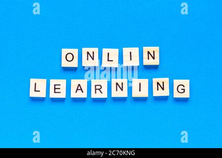 concepts d'apprentissage en ligne écrits en lettres de bois sur fond bleu. vue de dessus d'une mise en page plate, école en ligne. une nouvelle forme d'apprentissage Banque D'Images