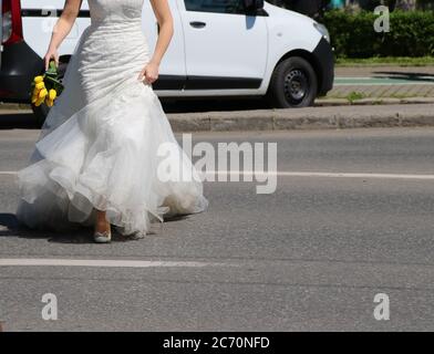 photographies urbaines d'une mariée portant une robe blanche et portant un bouquet de tulipes jaunes entre ses mains Banque D'Images