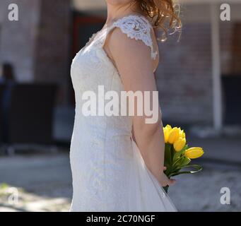 photographies urbaines d'une mariée portant une robe blanche et portant un bouquet de tulipes jaunes entre ses mains Banque D'Images