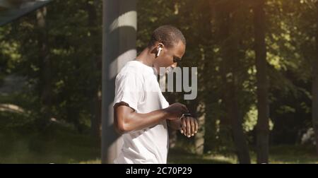 Homme afro-américain dans le casque vérifiant son activité sur SmartWatch Banque D'Images