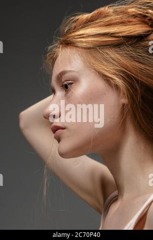 Émotions profondes. Portrait de mode de la belle femme à tête rouge isolée sur fond gris studio. Concept de beauté, de soins de la peau, de mode et de style. Œuvres d'art, portrait moderne et tendance. Modèle attrayant. Banque D'Images