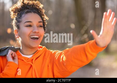 Portrait extérieur de la belle course mixte biracial afro-américaine jeune femme adolescente agitant et souriant avec des dents parfaites Banque D'Images