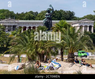 Munich, Allemagne. 13 juillet 2020. Une petite oasis de sable avec 13 palmiers (palmiers dattiers, ventilateurs et chanvre) et 30 chaises longues ont été construites sur une partie de la Theresienwiese par l'association environnementale Green City et la ville de Munich. En arrière-plan, vous pouvez voir la Bavière, qui donne sur la région. À cette époque de l'année, l'Oktoberfest est déjà en plein essor et doit être annulée cette année en raison de la crise de la couronne. Crédit : Peter Kneffel/dpa/Alay Live News Banque D'Images