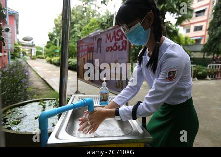 Yangon, Myanmar. 13 juillet 2020. Un élève portant un masque se lave les mains à une école le jour de l'inscription à Yangon, au Myanmar, le 13 juillet 2020. Le Myanmar a lancé mardi les inscriptions à l'école pour l'année scolaire 2020-2021, qui a été retardée en raison de la pandémie COVID-19. Crédit: U Aung/Xinhua/Alay Live News Banque D'Images