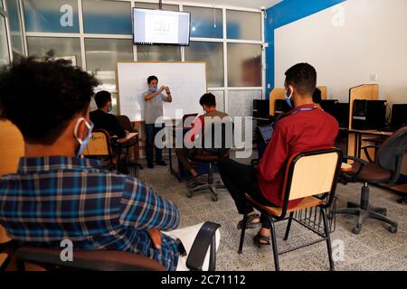 Sanaa, Yémen. 12 juillet 2020. Les étudiants portant un masque facial protecteur sont assis à distance alors qu'ils reprennent leurs études dans une université de Sanaa, Yémen, le 12 juillet 2020. Credit: Mohammed Mohammed/Xinhua/Alay Live News Banque D'Images