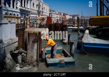 VENISE ITALIE - 09 JUILLET 2020 : un ouvrier travaille dans un canal de Venise, en face de la Piazza San Marco Banque D'Images