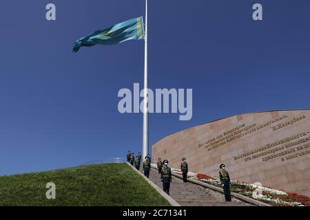 Nur-Sultan, Kazakhstan. 13 juillet 2020. Un drapeau national kazakh vole en Berne pour pleurer les victimes de la COVID-19 au parc commémoratif Atameken Ethno à Nur-Sultan, Kazakhstan, le 13 juillet 2020. Le Kazakhstan a pleuré lundi des citoyens qui sont morts de la COVID-19 un jour de deuil national. À 12 h, heure locale (0600 GMT), le pays a observé une minute de silence pour rendre hommage aux victimes de la COVID-19. Les drapeaux des gouvernements central et local et les missions diplomatiques étrangères ont été en Berne pour pleurer les victimes. Les chaînes de télévision ont suspendu la diffusion d'émissions de divertissement tandis que websit Credit: Banque D'Images