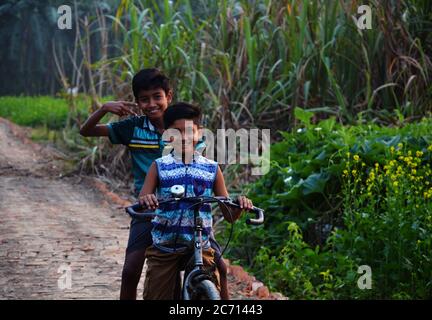 Deux adolescents indiens en vélo dans une route de village, en se concentrant sur une sélection Banque D'Images