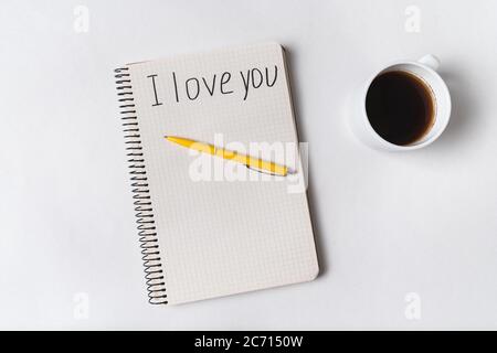 Je t'aime, écrit sur un ordinateur portable. Café du matin et message pour nous. Fond blanc. Banque D'Images