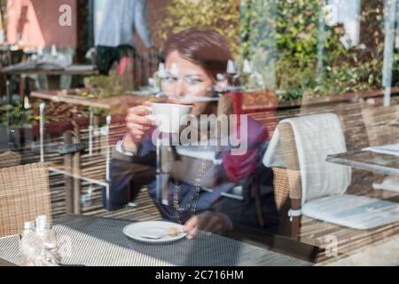 Femme assise dans un restaurant en plein air et buvant du café en Suisse. Banque D'Images