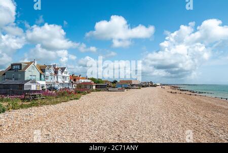 Pevensey Bay, East Sussex, Angleterre. Maisons typiques en bord de mer le long de la côte de la plage de galets sur la côte sud de l'Angleterre. Banque D'Images