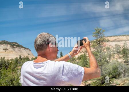 Vue arrière du touriste mâle en t-shirt prenant des photos du parc national. Concept de tourisme. Banque D'Images