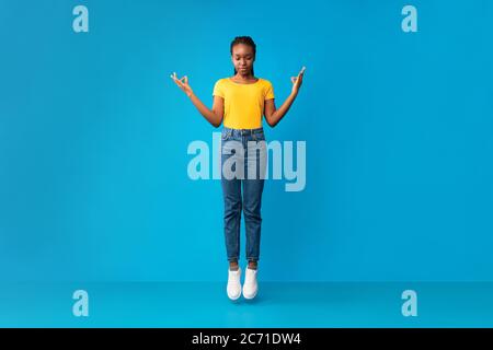 Fille millénaire afro-américaine méditant en milieu d'air sur fond bleu Banque D'Images