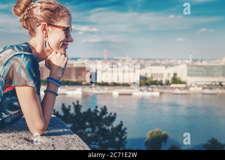 Jeune femme urbaine à tête rouge regardant vers le bas vers la ville en été, vue profil, Budapest, Hongrie Banque D'Images