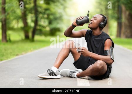 Bien adapté sportif noir boire des protéines, assis sur la voie Banque D'Images