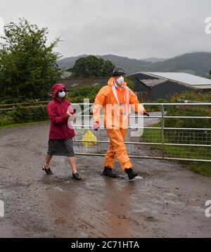 Karen Wright (à gauche), directrice de la santé publique de la GCC de Herefordshire, assainit avant d'ouvrir une porte pour faire un communiqué de presse à l'extérieur de la ferme de Rook Row à Mathon, près de Malvern, dans le Herefordshire, où 73 cas positifs de coronavirus ont été confirmés. Banque D'Images