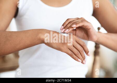 Traitement de l'eczéma. Femme noire appliquant de la crème hydratante sur la peau de la main Banque D'Images