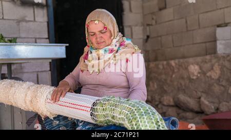 Adiyaman, Turquie - juin 2018: Femme turque locale rassemblant des feuilles de tobocco avec une machine plus tard pour les laisser sécher, Turquie Banque D'Images