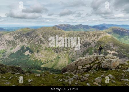 Une randonneur solitaire qui regarde à travers les collines et les montagnes du parc national du Lake District, en Angleterre, depuis le sommet de Pillar. Banque D'Images