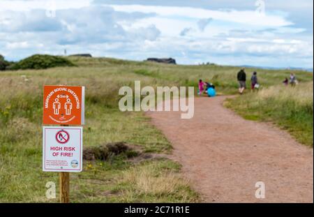 East Lothian, Écosse, Royaume-Uni, 13 juillet 2020. Météo au Royaume-Uni : couvert à la plage de Yellowcraig après la pluie. Des mesures de distanciation sociale sont en place sur le trajet entre le parc automobile et la plage pendant la pandémie du coronavirus Covid-19, tandis que les gens marchent le long de la piste de marche avec un avis de rester à 2 mètres d'écart et un avertissement sur le risque d'incendie Banque D'Images