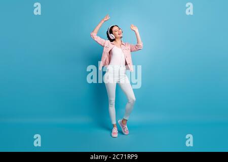 Photo pleine longueur de belle dame gaie à l'écoute cool moderne technologie écouteurs yeux fermés apprécier la musique danse porter décontracté rose pantalon de veste Banque D'Images