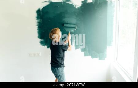 les enfants peignent les murs avec un rouleau. Banque D'Images