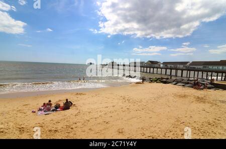 Southwold, Royaume-Uni. 12 juillet 2020. Les gens s'assoient sur la large plage de sable qui surplombe la jetée. Avec les plages d'Angleterre maintenant entièrement ouvertes avec seulement des mesures de distance sociales en vigueur, les gens prennent l'occasion de visiter certaines stations balnéaires. Southwold est une station balnéaire anglaise pleine de charme ancien et célèbre pour ses 300 cabanes de plage aux couleurs vives. Il y avait plein de gens à l'extérieur et sur la plage de sable et sur la jetée. Crédit : SOPA Images Limited/Alamy Live News Banque D'Images