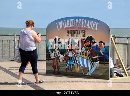 Southwold, Royaume-Uni. 12 juillet 2020. Une femme prend une photo de l'amusant pirate « Je suis allé à pied avec vous à la mer ». Avec les plages d'Angleterre désormais entièrement ouvertes avec seulement des mesures de distance sociales en vigueur, les gens prennent l'occasion de visiter quelques stations côtières. Southwold est une station balnéaire anglaise pleine de charme ancien et célèbre pour ses 300 cabanes de plage aux couleurs vives. Il y avait plein de gens à l'extérieur et sur la plage de sable et sur la jetée. Crédit : SOPA Images Limited/Alamy Live News Banque D'Images