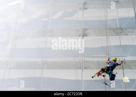 Lave-glace fonctionne sur le mur d'un bâtiment en verre. Banque D'Images