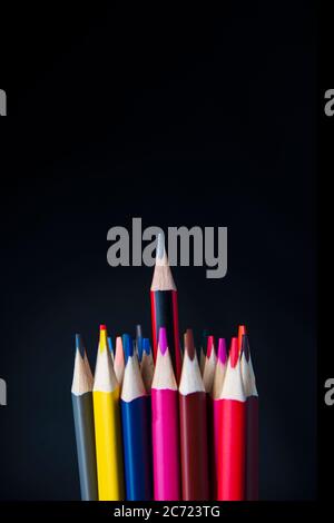Les bouts de crayons de couleur et au centre d'un simple crayon sur un fond noir avec place pour le texte Banque D'Images